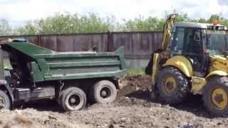 Экскаватор-погрузчик New Holland LB115  грузит самосвал КАМАЗ.