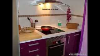 Muebles de cocina en berengena alto brillo y encimera Compac blanco absolut