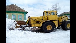 Трактор К-700 гребёт снег по улице весной