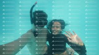 Bloggers young guy and girl diving underwater in pool making selfie and kissing.