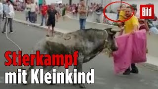 Mann kämpft mit Kind auf dem Arm gegen einen Stier