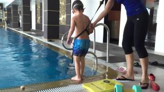 Марат с тренером учится плавать в бассейне Kid swimtraining in swimming pool