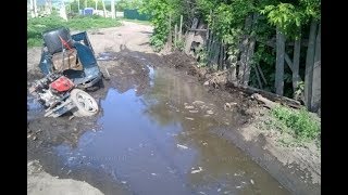 Трактор вытаскивает мотоблок с грязи.